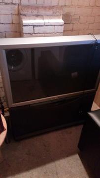 SONY 42 INCH REAR PROJECTION TV ON STAND WITH SPEAKERS TO THE BASE CAN BE SEEN WORKING