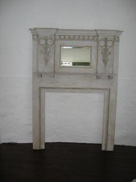 Fireplace in wood with mantlepiece and bevelled mirror above, 6ft 3ins tall with relief designs