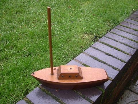 A small solidly made wooden boat with sail mast